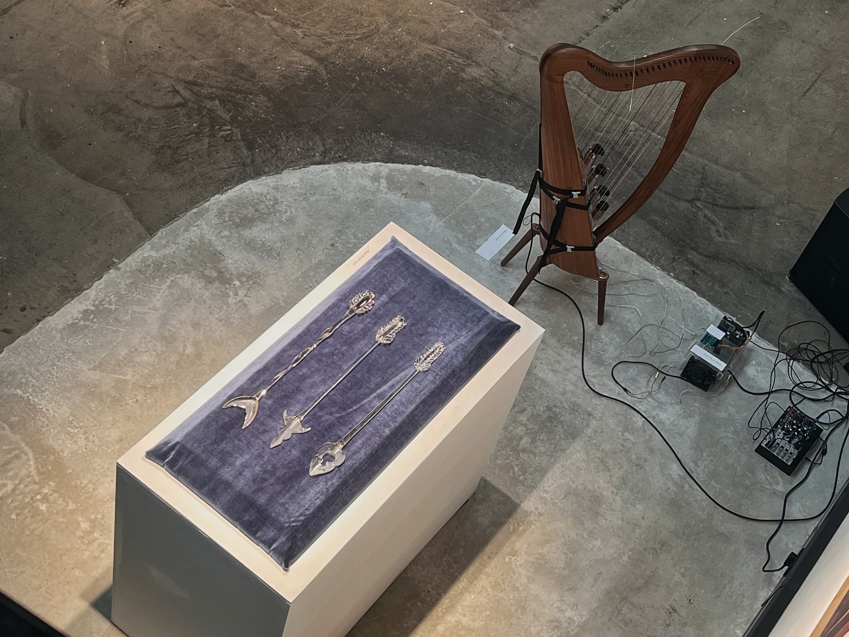 Bronze implements laid in a velvet-lined case beside a wooden lyre on the Standalone gallery floor.